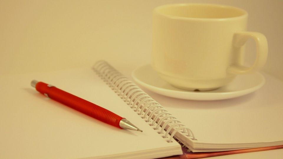 Defter, kalem ve kahve fincanı ile çalışma masası